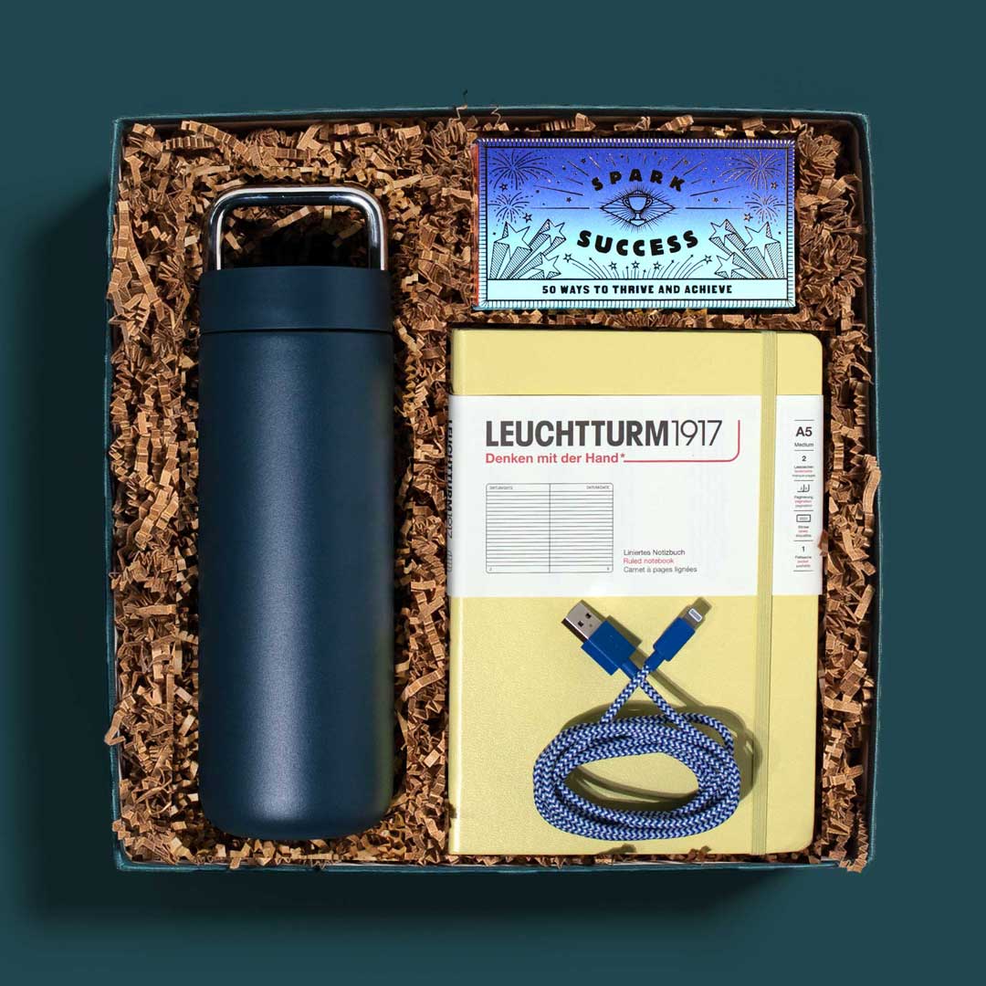 workplace new hire or anniversary gift box with a travel mug, notebook, charging cable and more